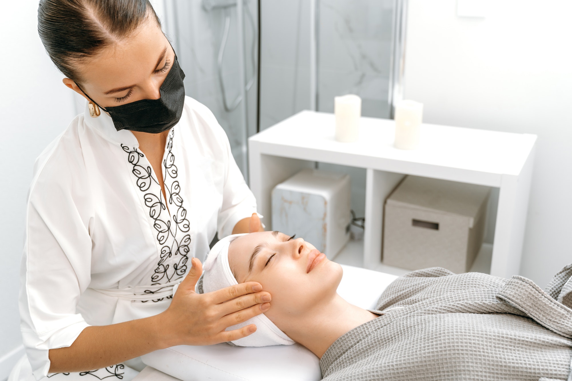 Facial massage in spa salon. Woman massage therapist makes face massage to caucasian relaxed woman